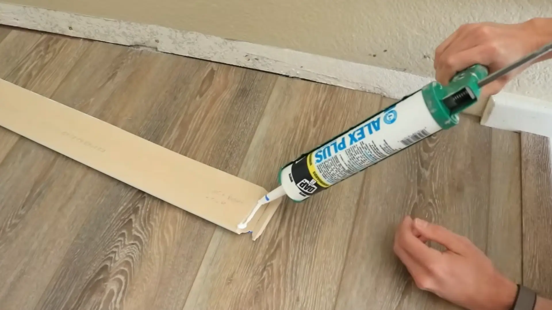 person applying caulk to seam and join a longer baseboard run