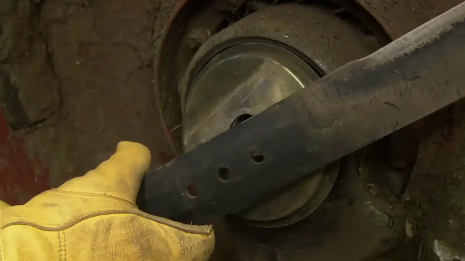 person reinstalling a lawn mower blade onto the spindle with a wrench