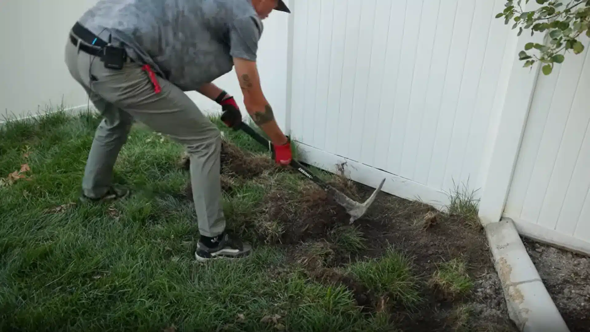 person removing natural grass with a shovel while preparing the ground for artificial grass installation