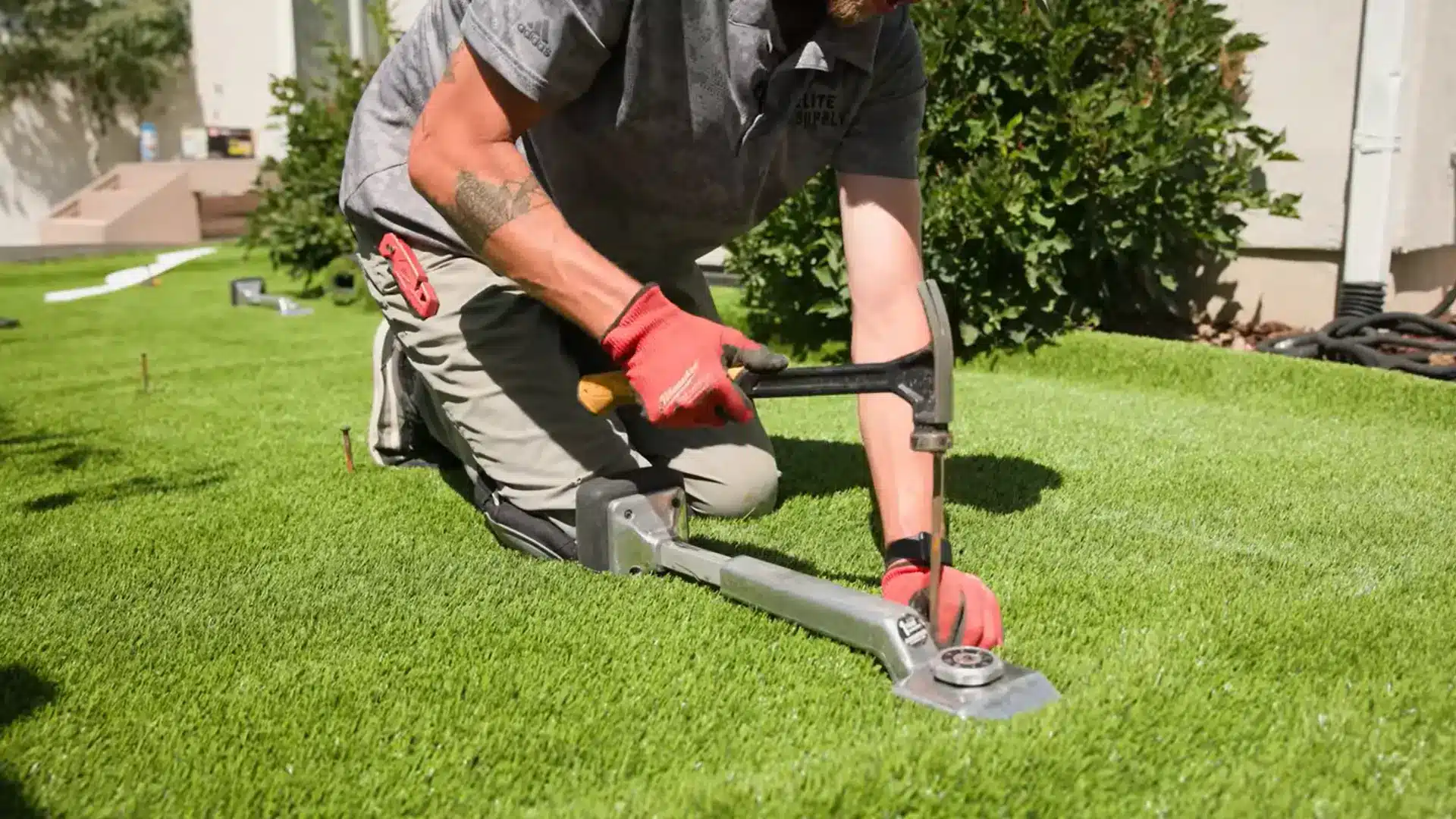 person securing artificial grass edges with landscape nails beside a neatly finished garden border