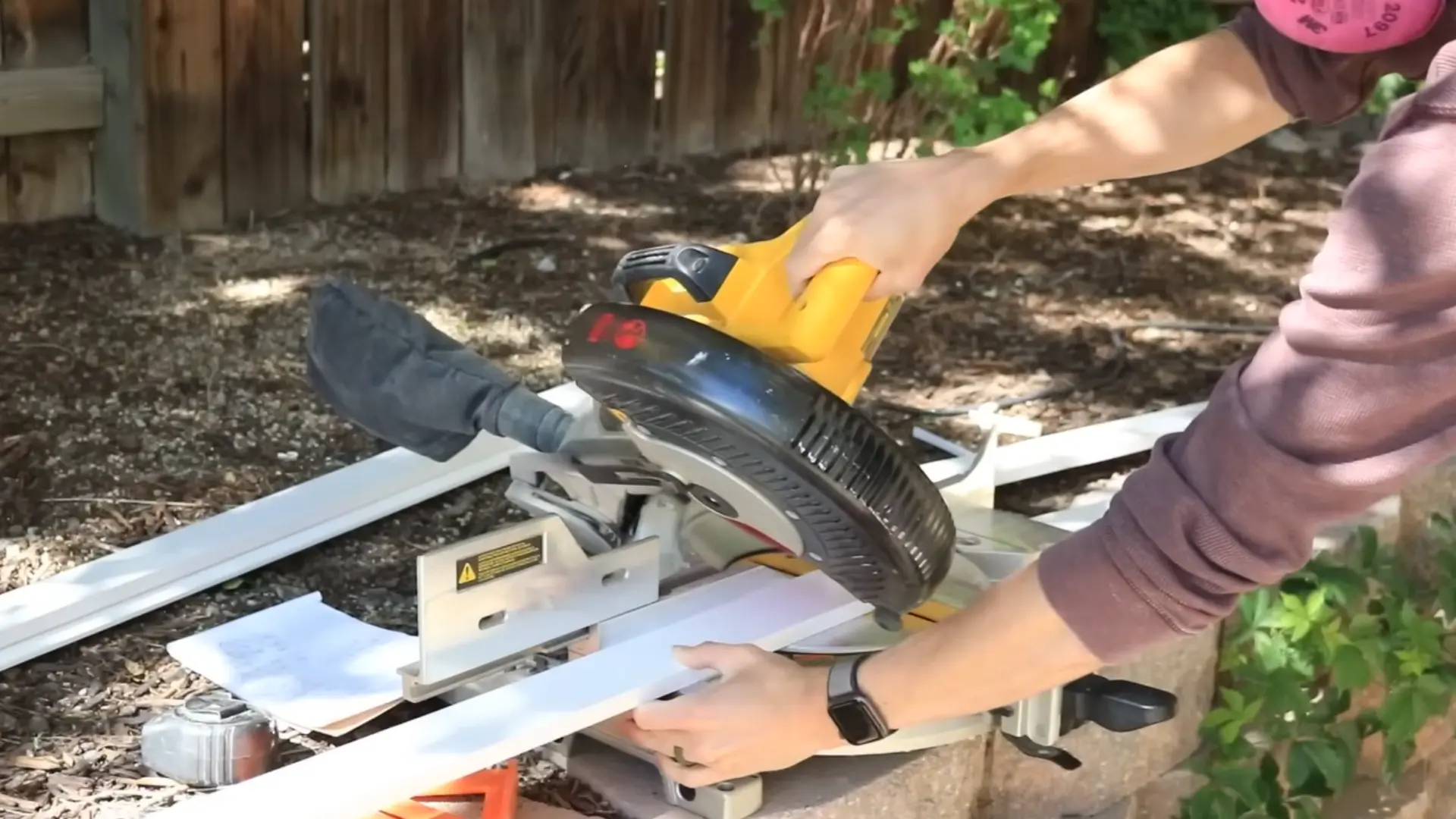 person using a miter saw to cut baseboard trim to size