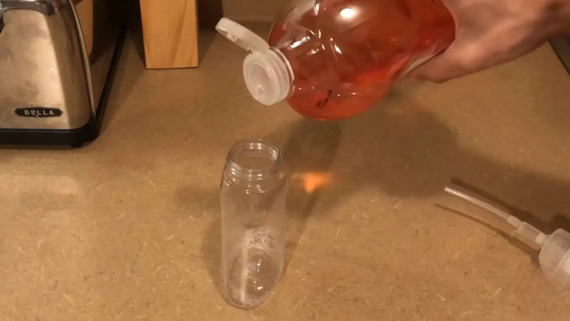pouring pink liquid hand soap into an empty foaming soap dispenser bottle