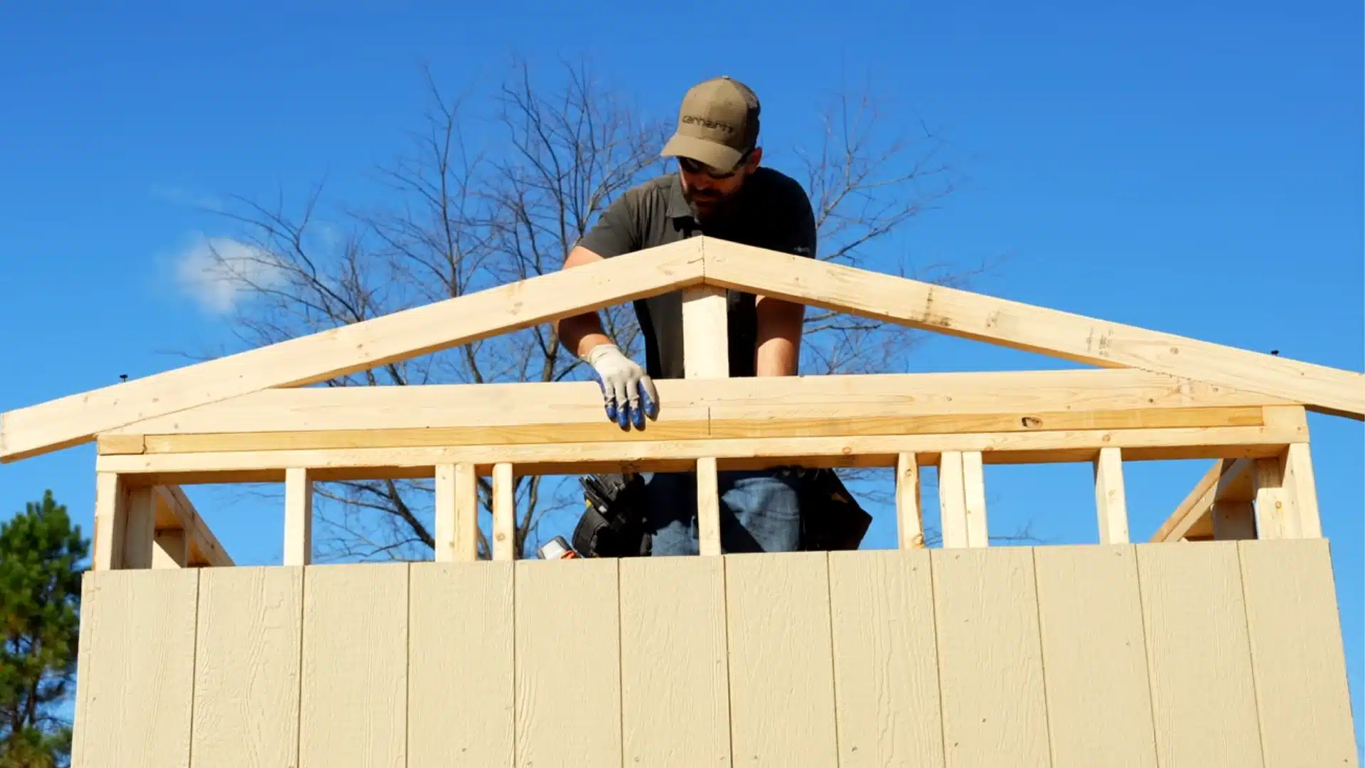 roof construction with trusses and plywood sheathing being installed under clear sky