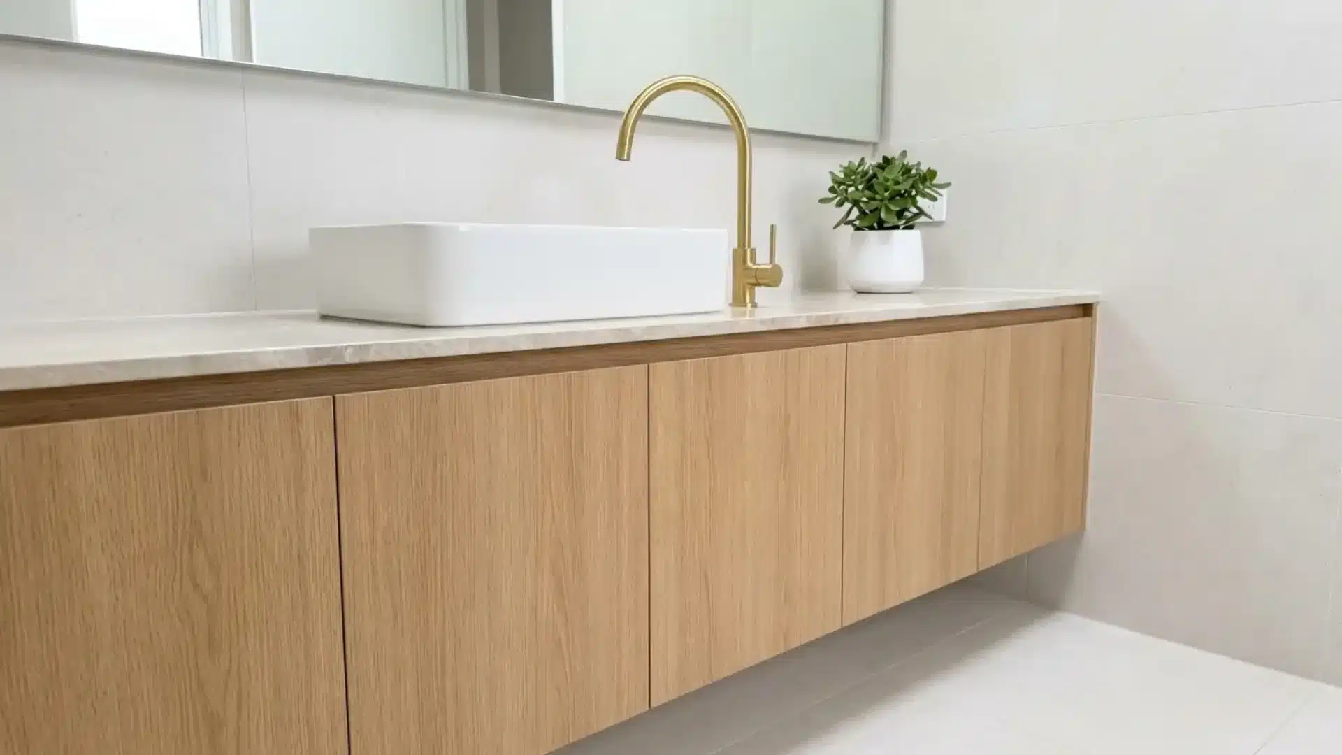 seamless wood cabinet vanity with no visible handles rectangular sink and small potted plant
