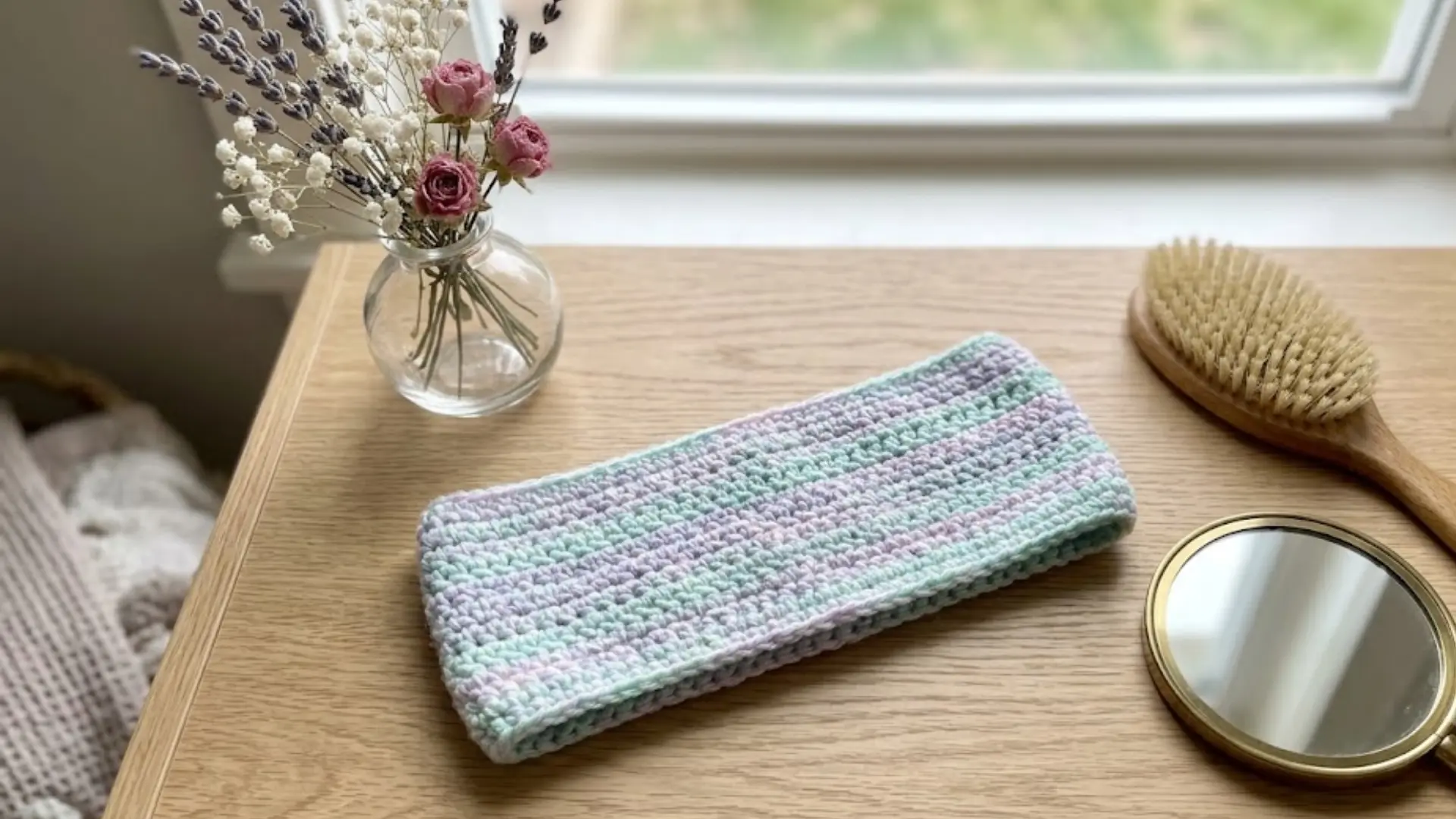 simple handmade crochet headband displayed on a wooden vanity with everyday accessories