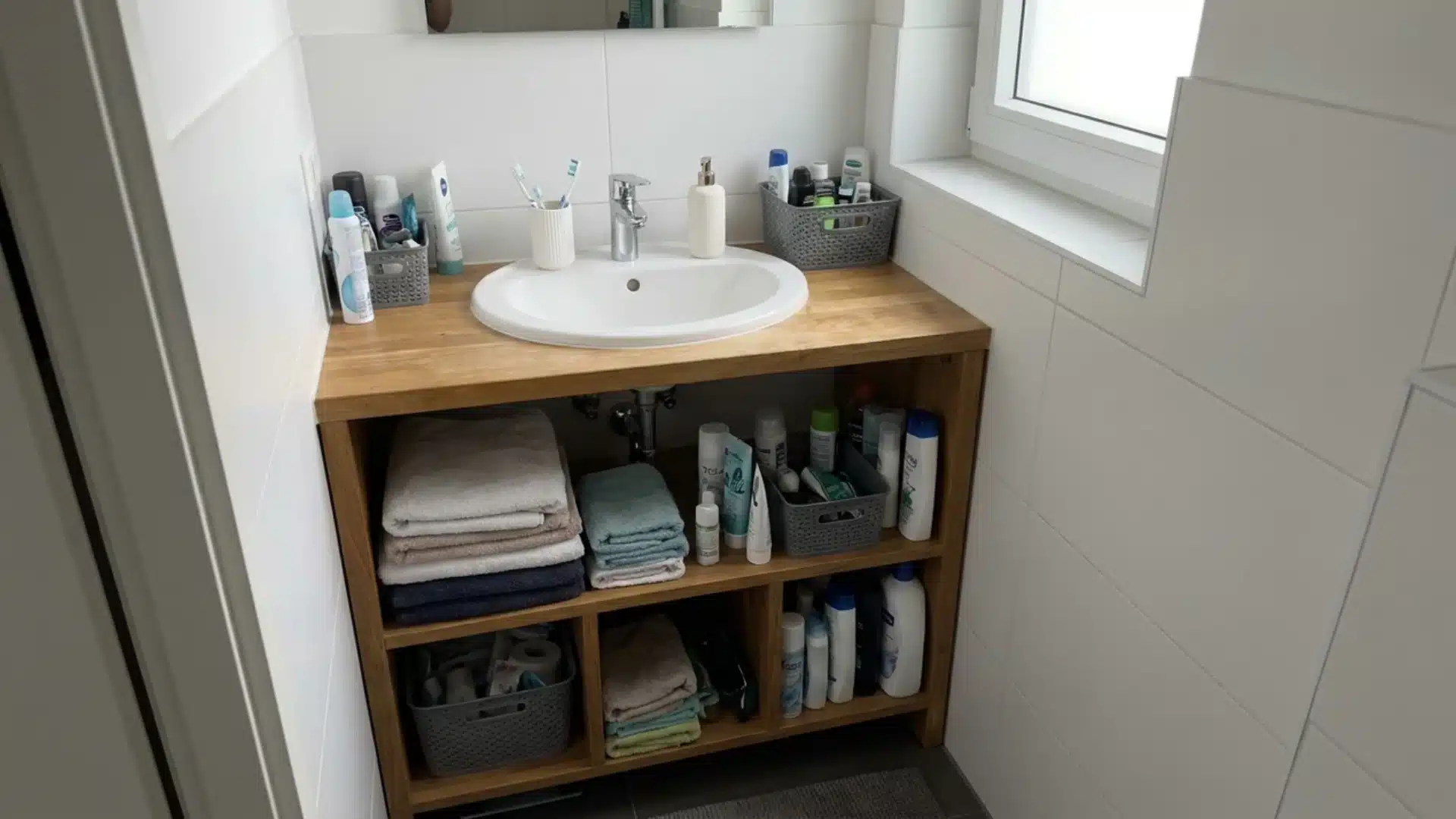 small open shelf vanity with round sink exposed cubbies holding folded towels and baskets