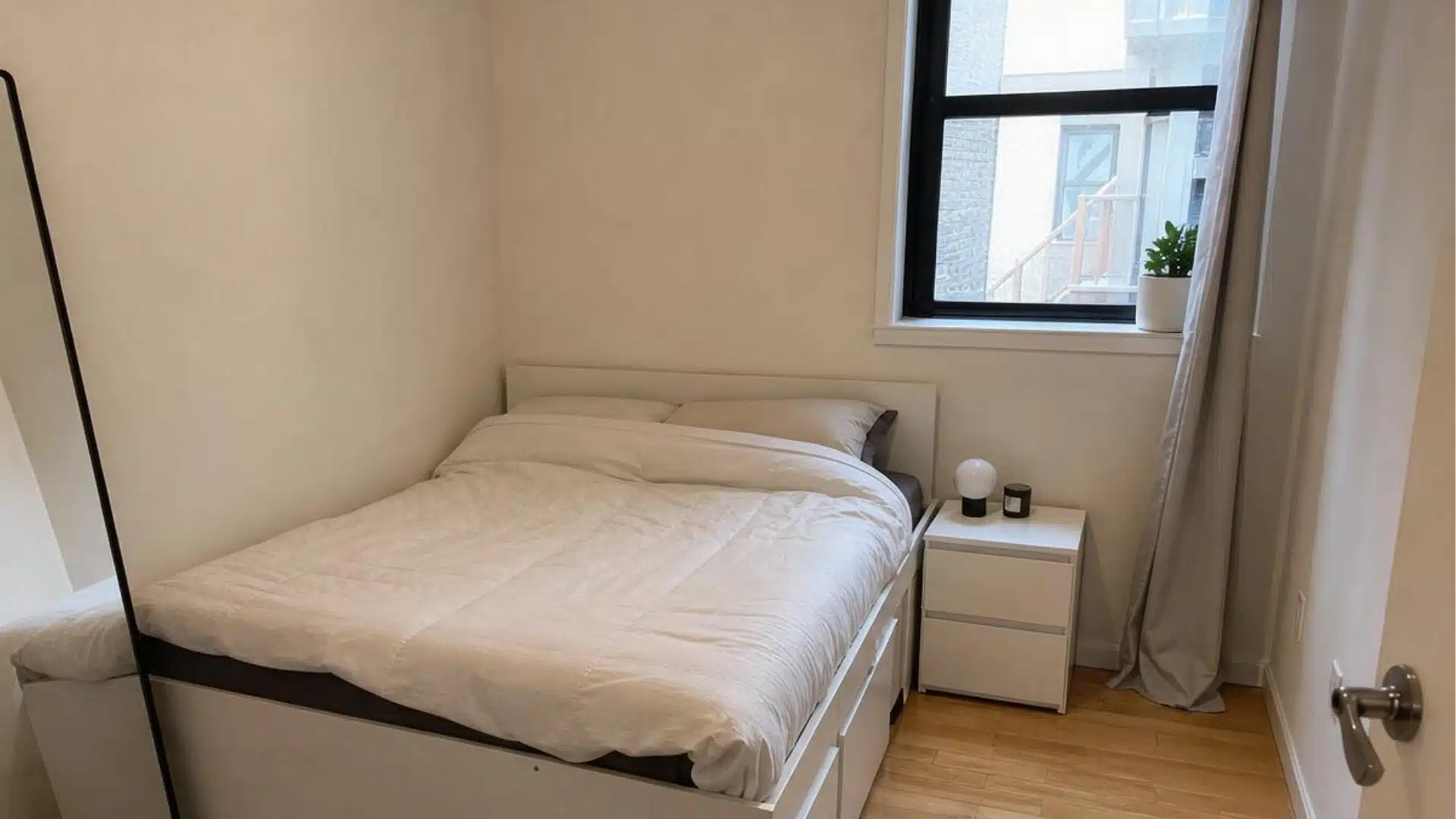 small warm neutral bedroom with storage bed, white nightstand, and curtains