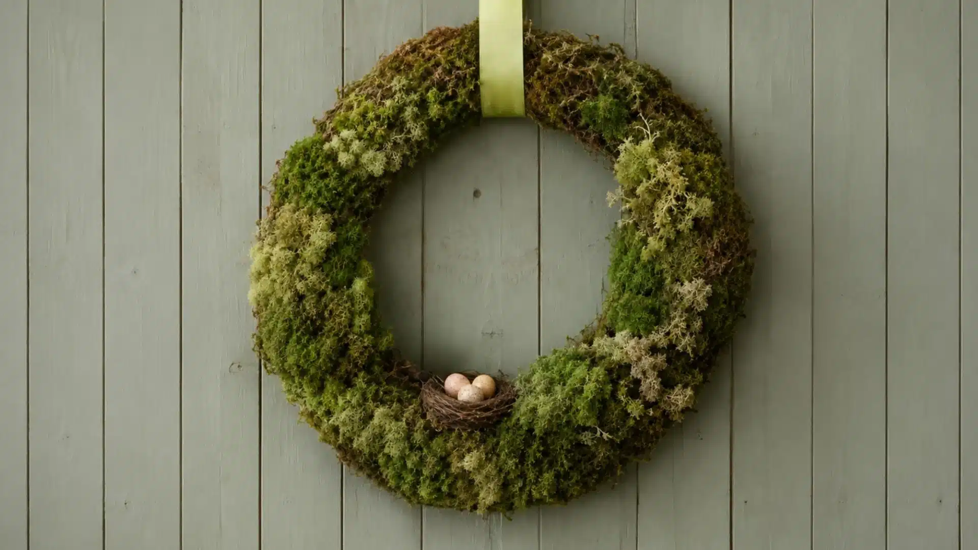 spring moss wreath with a decorative nest and speckled eggs and toy bird