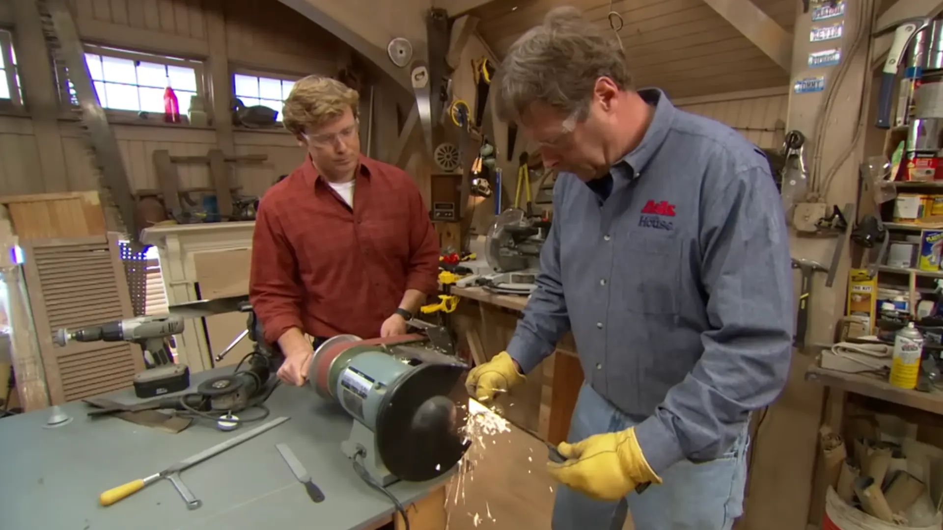 two men sharpening a mower blade on a bench grinder with sparks flying