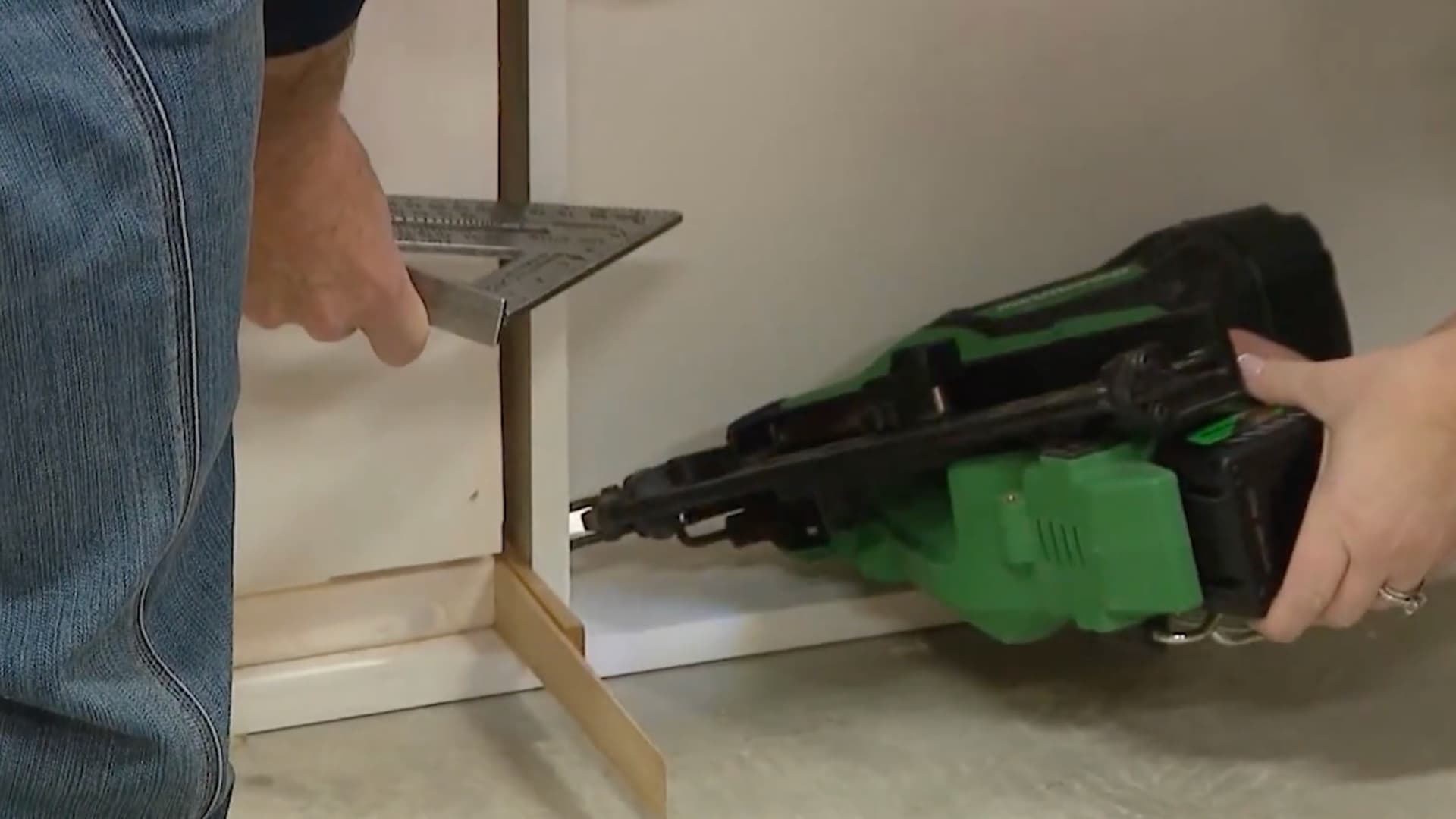 two people pushing a door jamb flush against the wall before nailing it in place