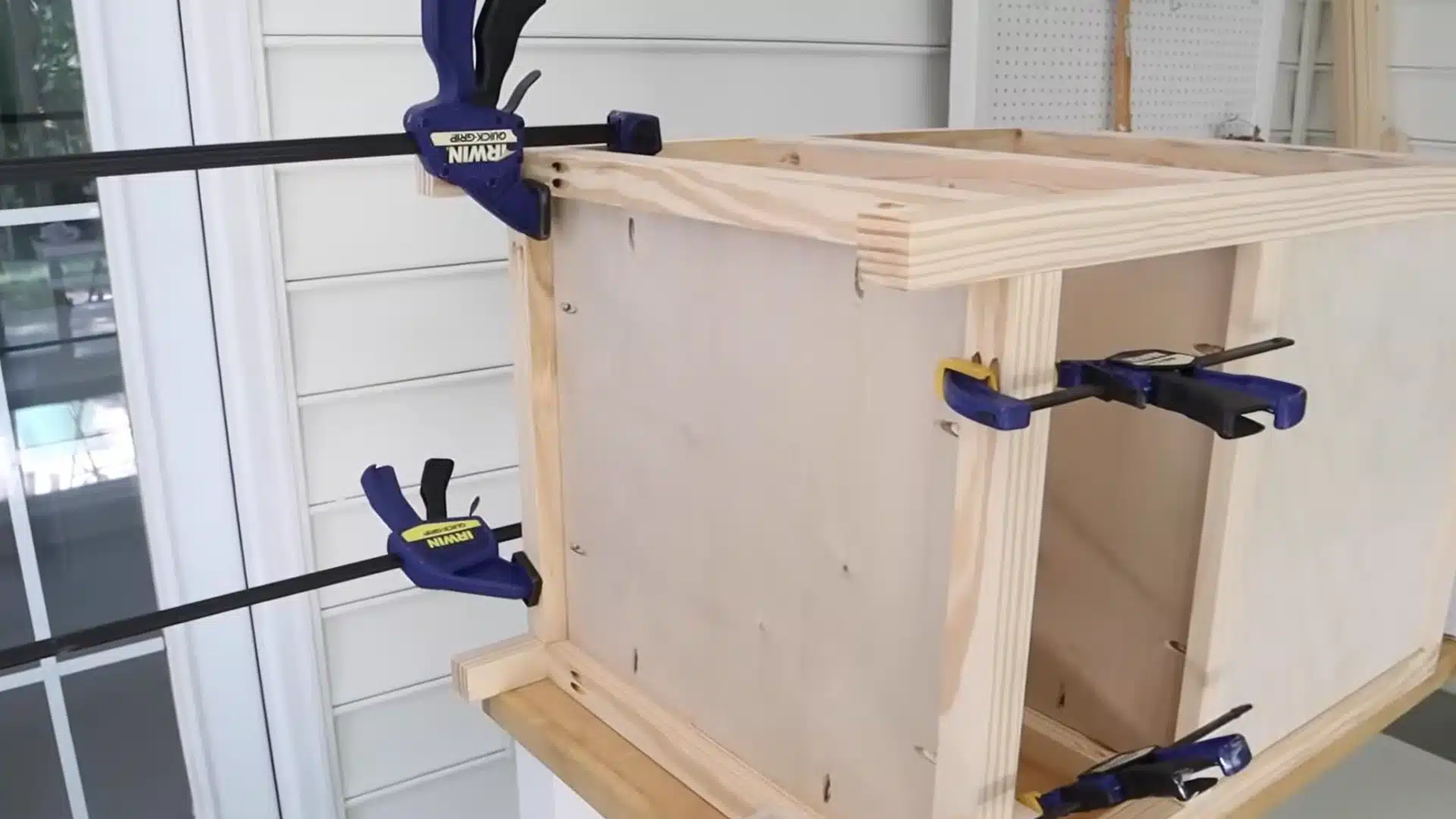vanity cabinet frame held together with several clamps while glue sets on the front boards