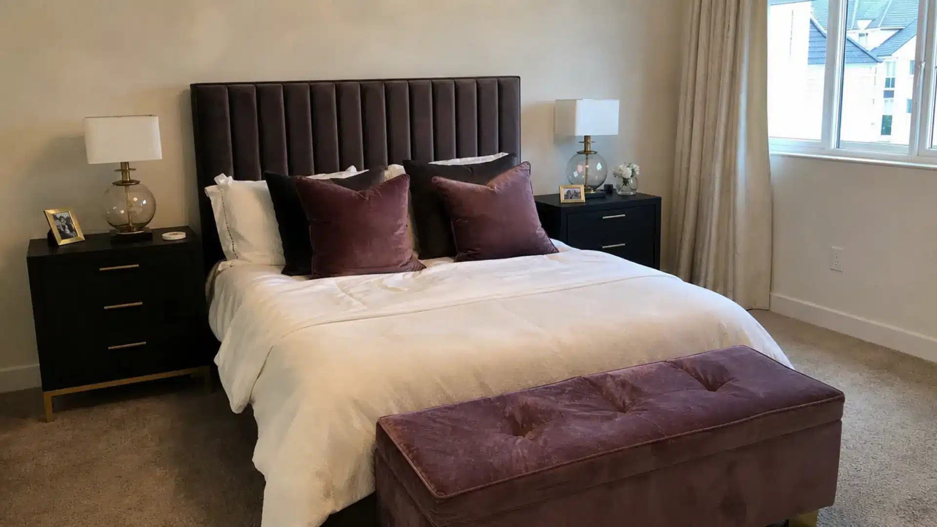 velvet channel headboard with plum pillows and tufted bench in neutral bedroom