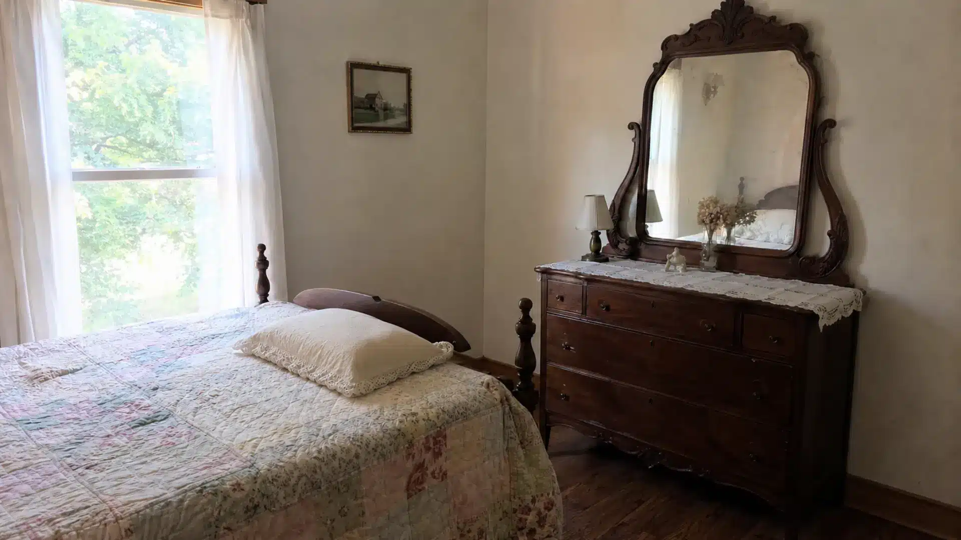 vintage neutral bedroom with antique wood dresser and ornate mirror