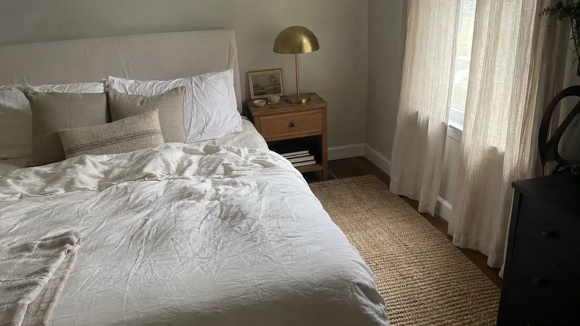 warm neutral bedroom with jute rug, brass lamp, and linen bedding on wood nightstand