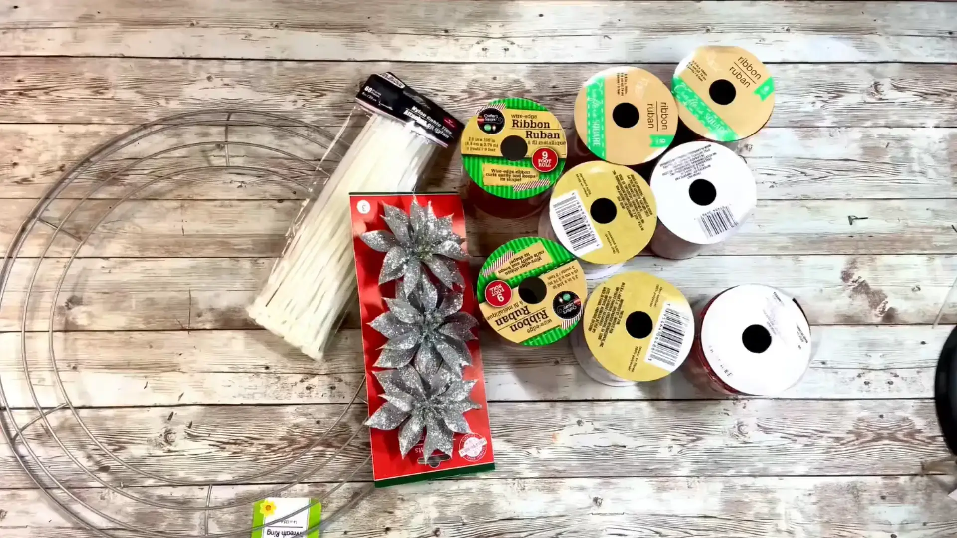 wreath frame, zip ties, christmas ribbons and silver flowers arranged for a diy ribbon wreath