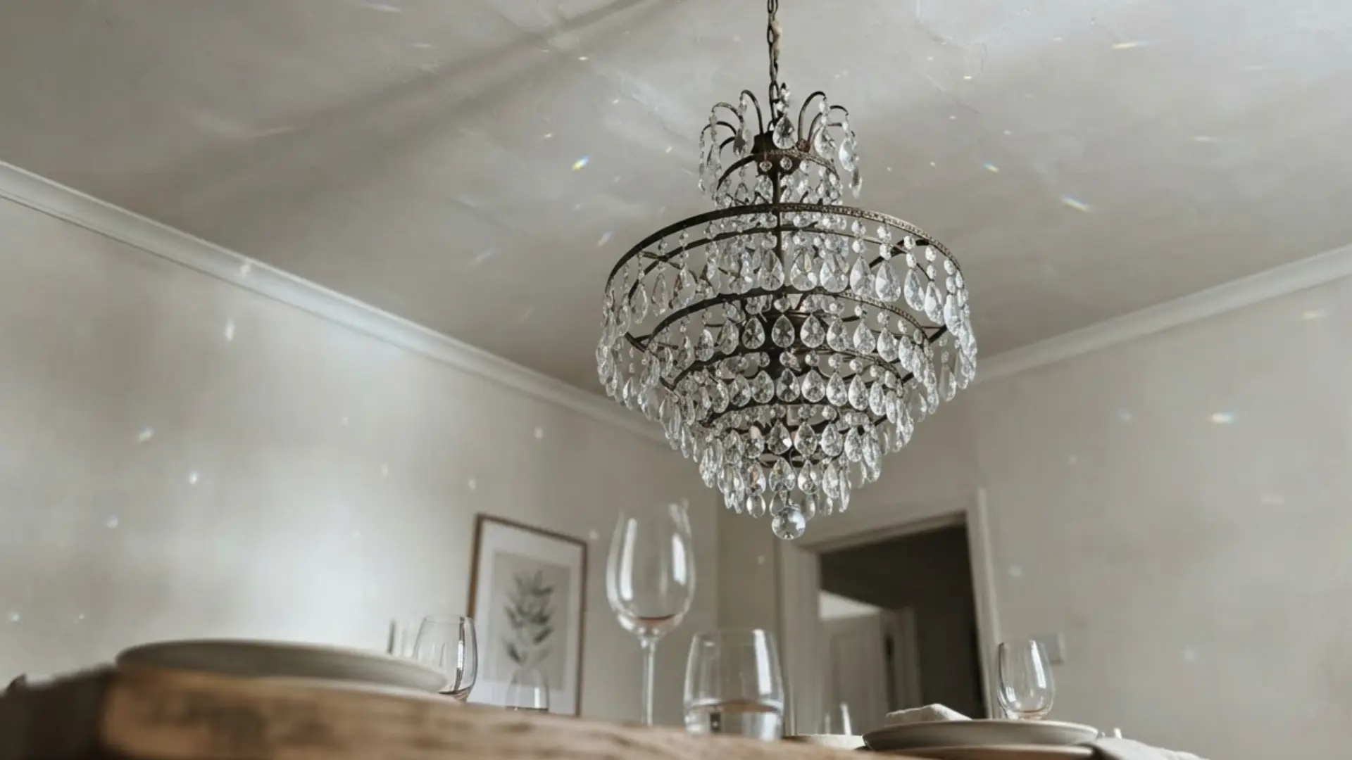crystal chandelier with layered glass drops hanging above a dining table with wine glasses