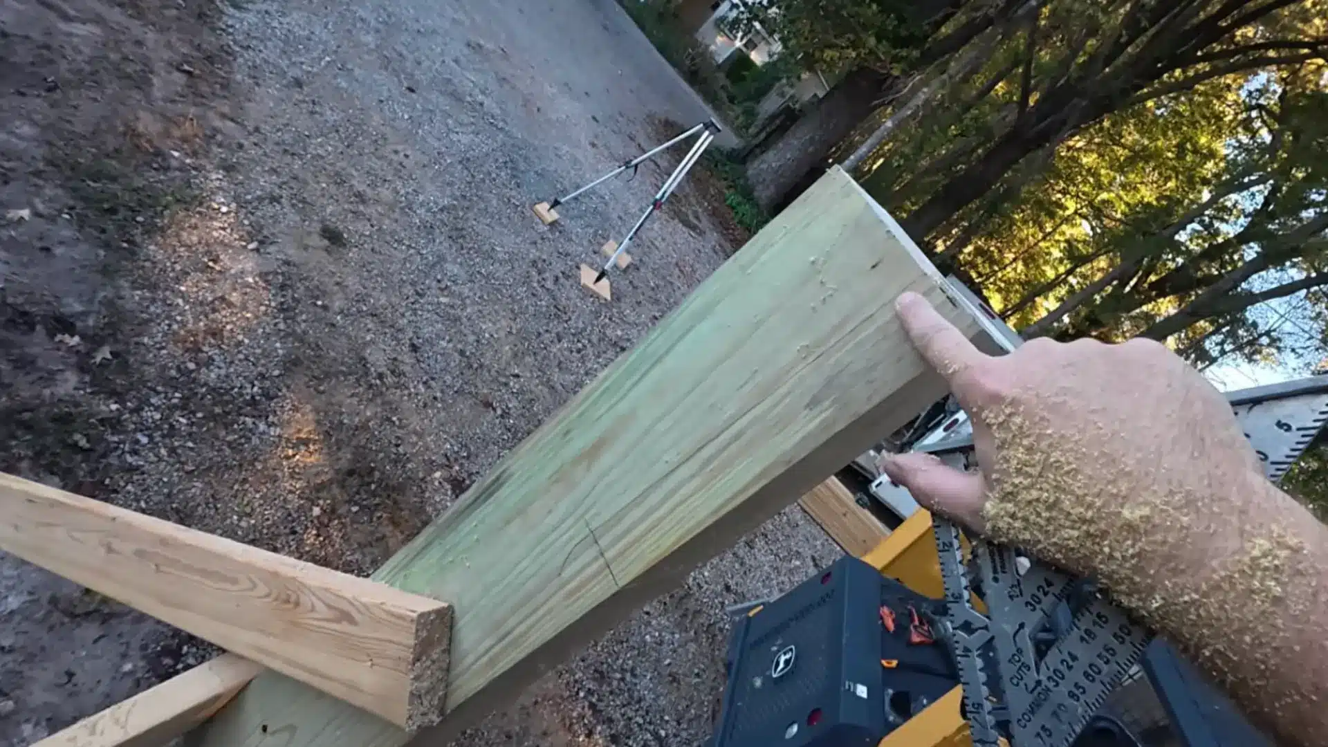 person holding a notched wooden beam while measuring and leveling it for a carport frame