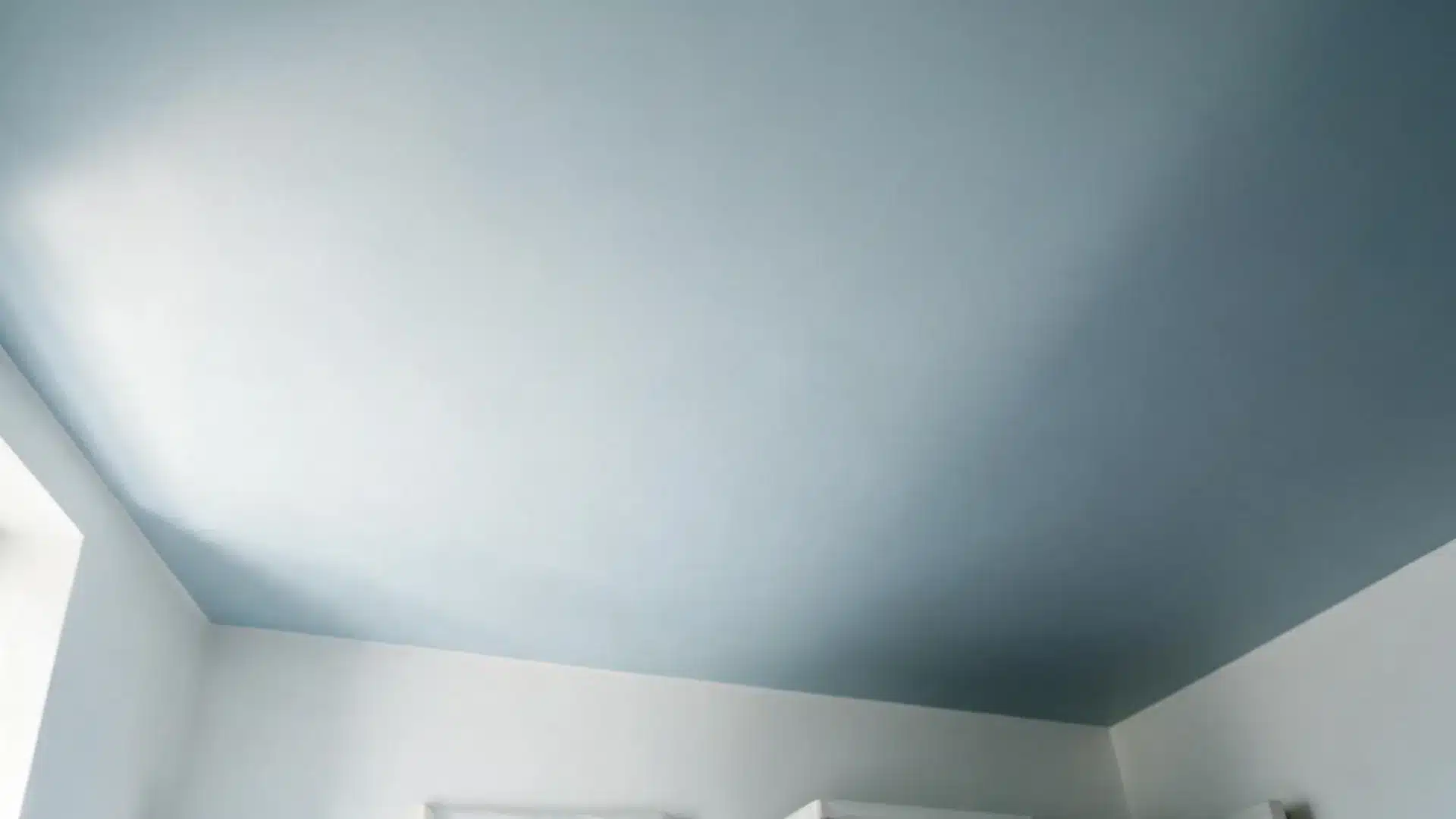 pale blue painted ceiling meeting white walls in the corner of a coastal bedroom with gentle natural light