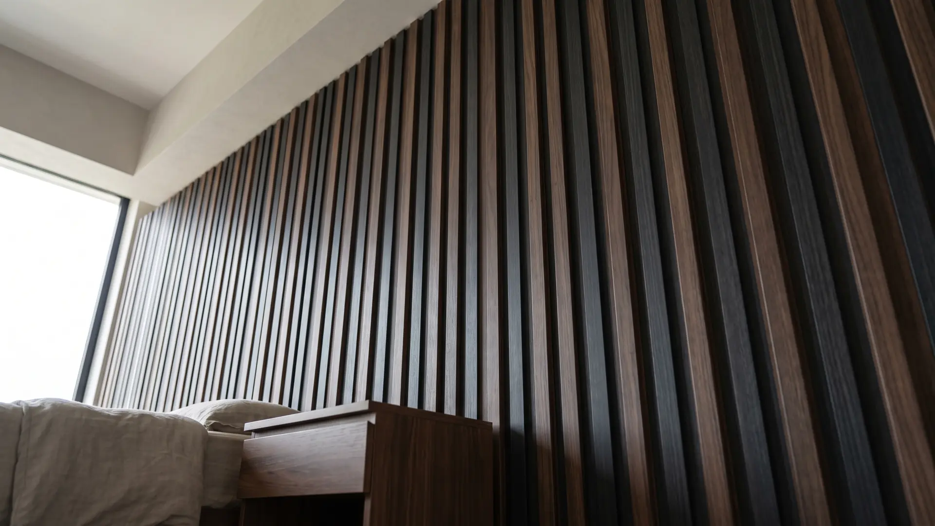 vertical dark wood slat wall behind a bed, adding texture and height to a modern bedroom